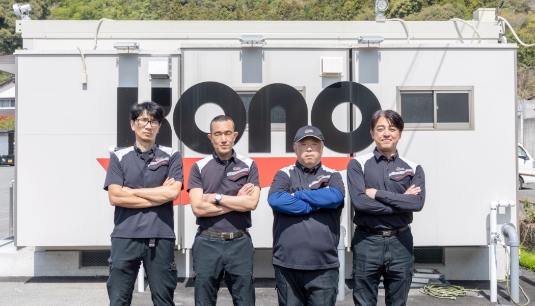 河野のロゴをバックにこちらを眺める社員たち